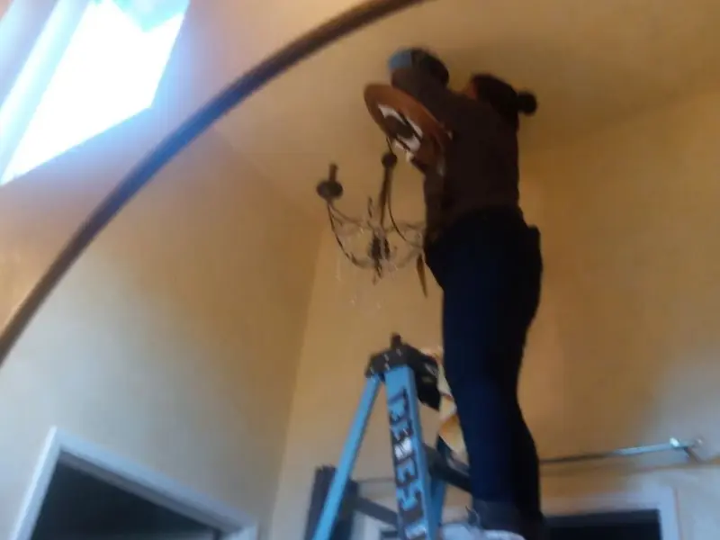Electrician installing a chandelier in a Winona residence